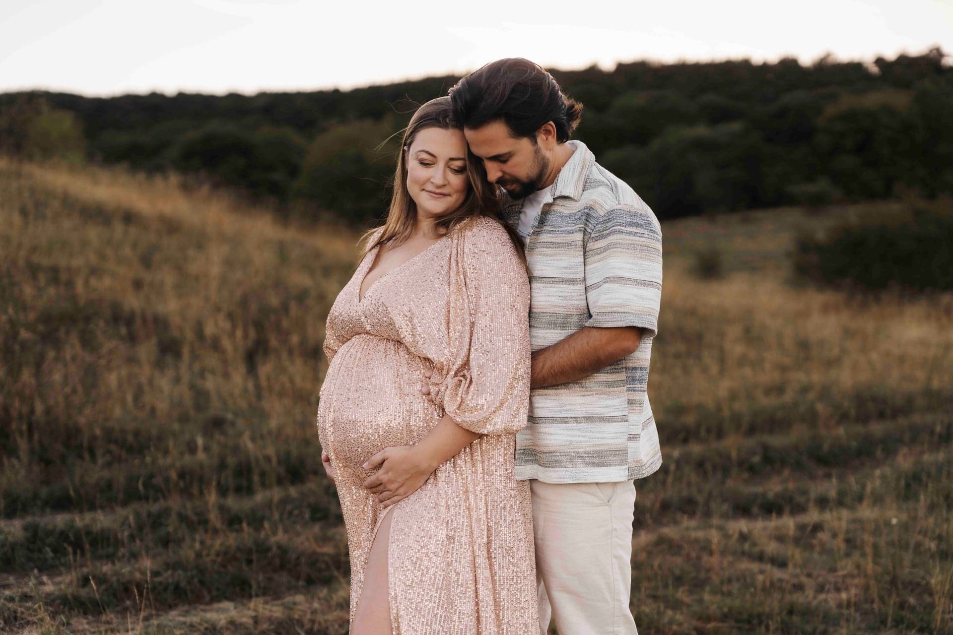 Babybauch Paar Fotografie Niederösterreich – Lucia lehnt sich an Max, Hände am Bauch
