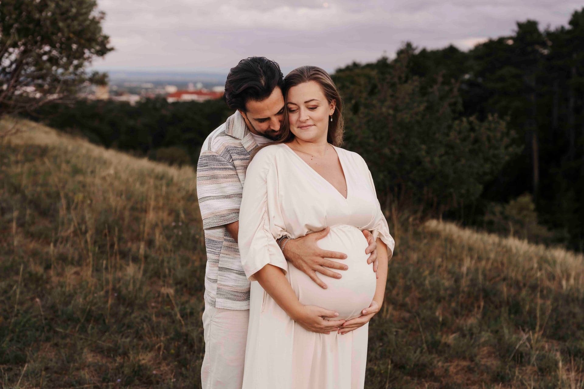 Babybauch Paar Fotografie Wien – Max hält Lucias Bauch, Blick über die Stadt im Abendlicht