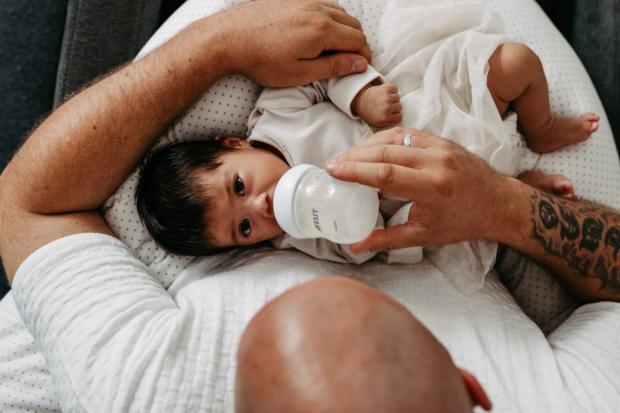 Newborn Homestory Wien – Papa gibt Baby die Flasche